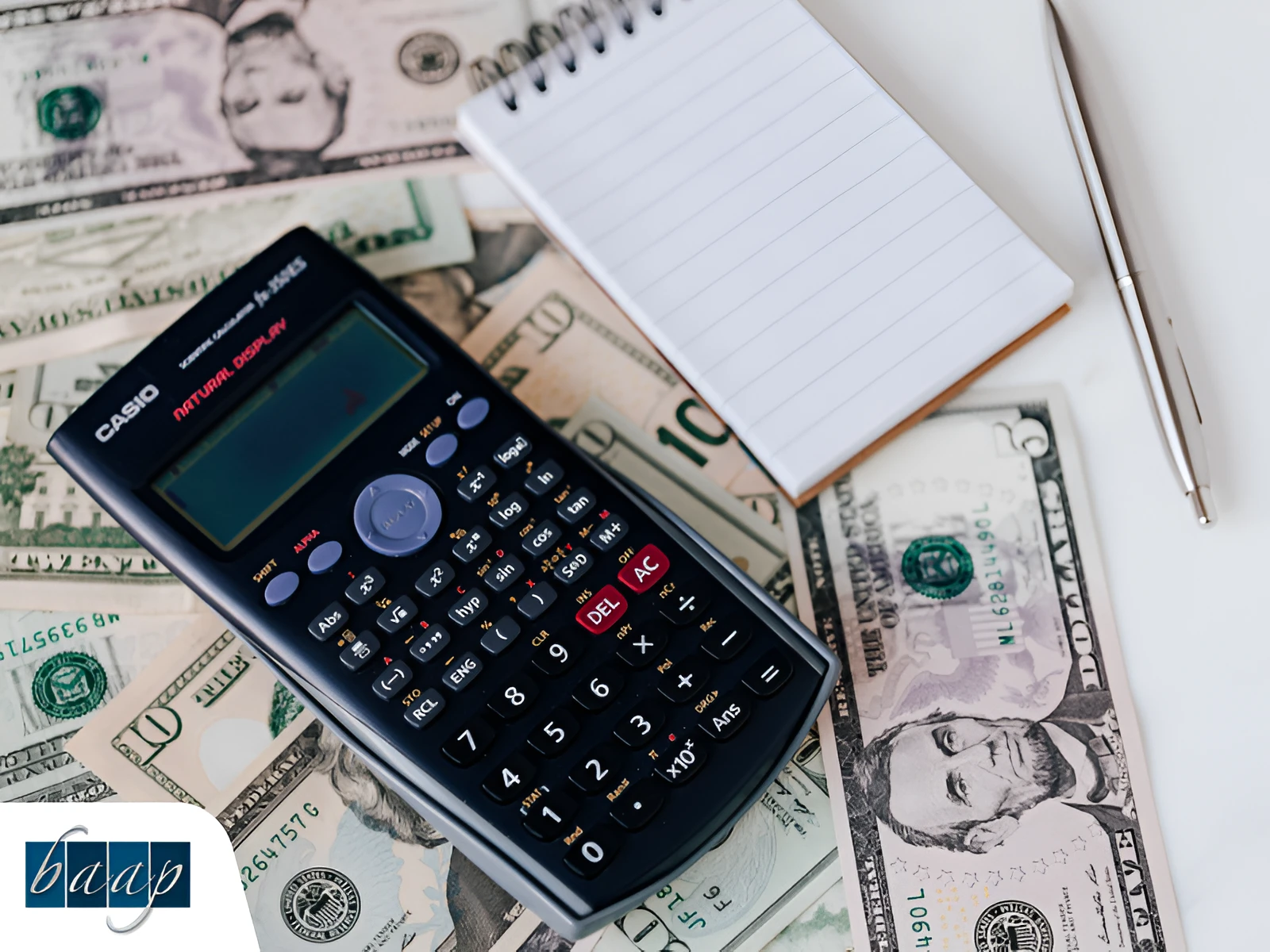 Calculator with cash, notepad, and pen symbolizing business budgeting